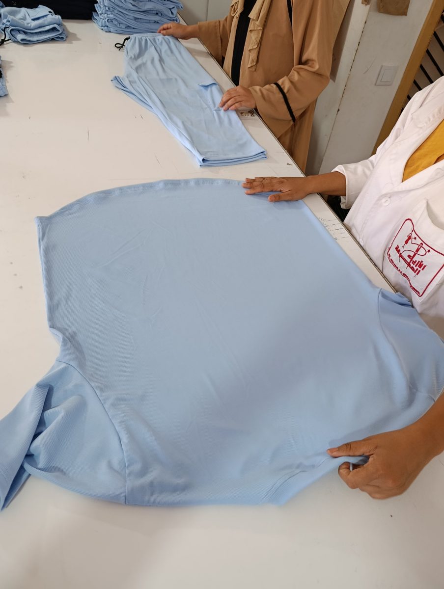 Couturières pliant des vêtements bleu ciel en atelier