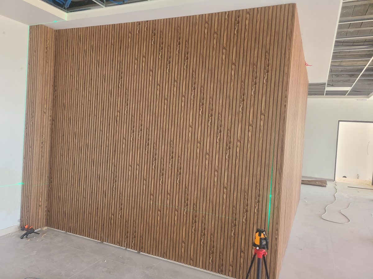 Habillage mural en tasseaux de bois effet noyer, en cours