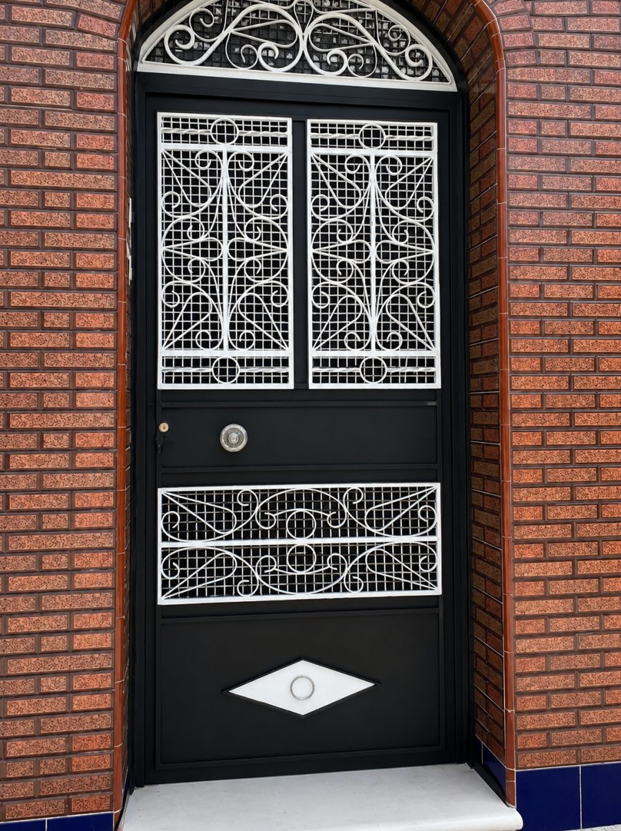 Porte d'entrée en fer forgé noir à grilles blanches ouvragées