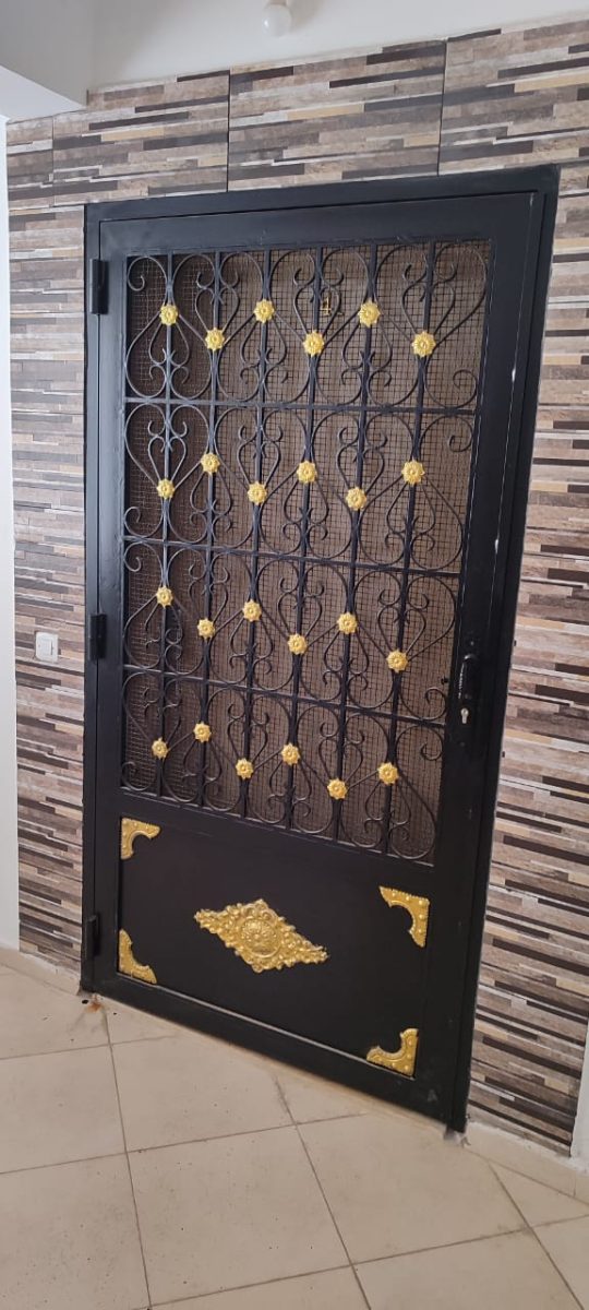 Porte d'entrée en fer forgé noir à volutes et rosaces dorées