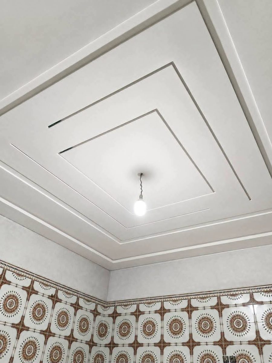 Faux plafond blanc à cadres concentriques et soubassement en zellige