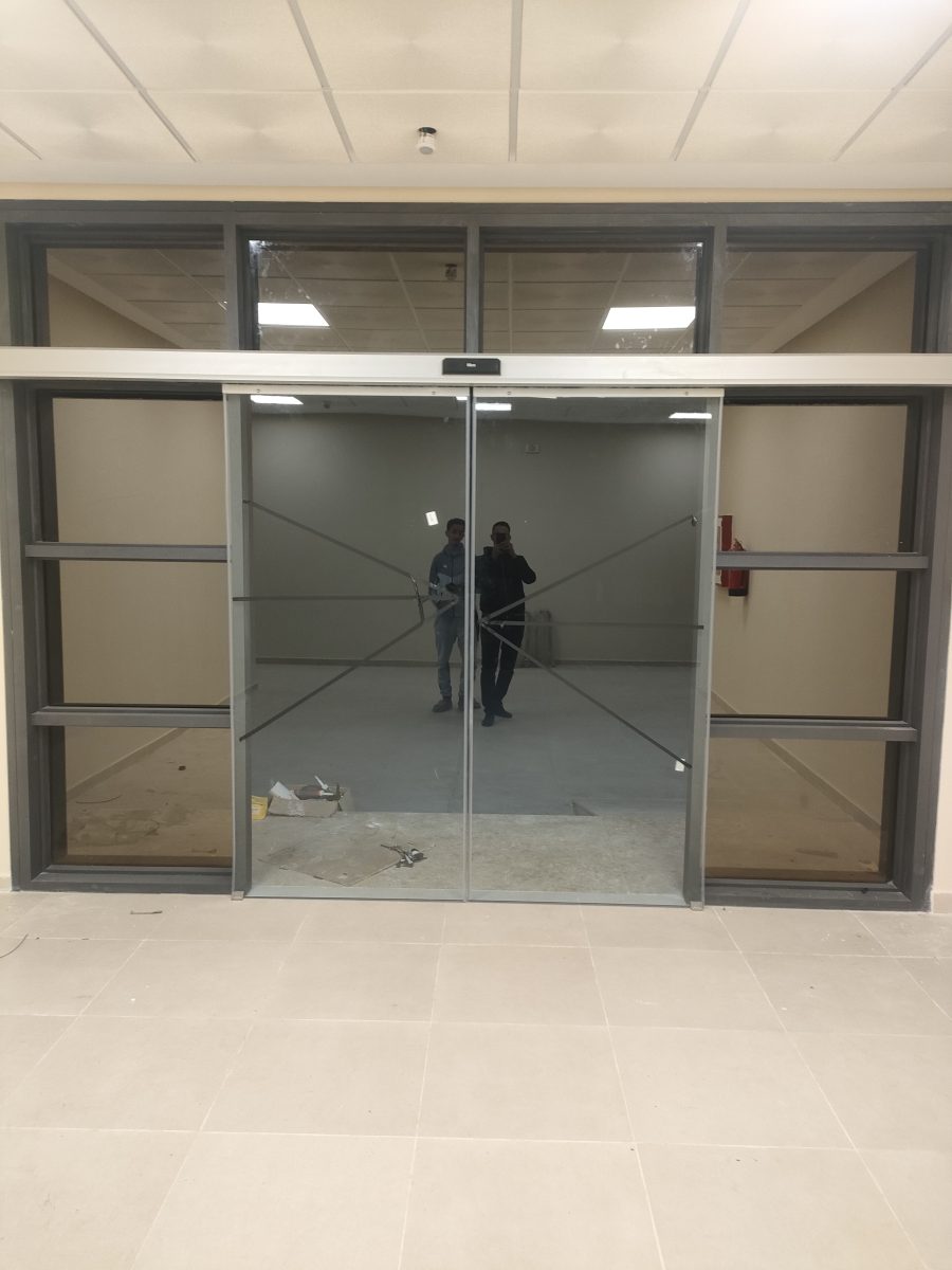 Porte automatique vitrée à châssis aluminium dans un local en finition