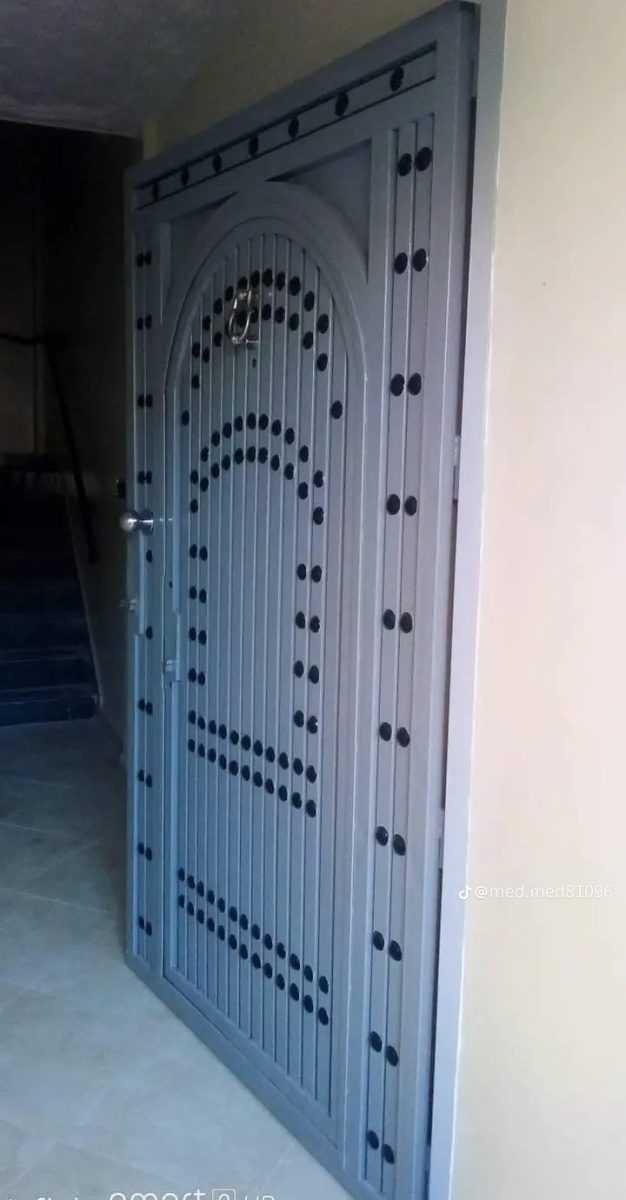 Porte d'entrée en acier gris à décor de clous en arc