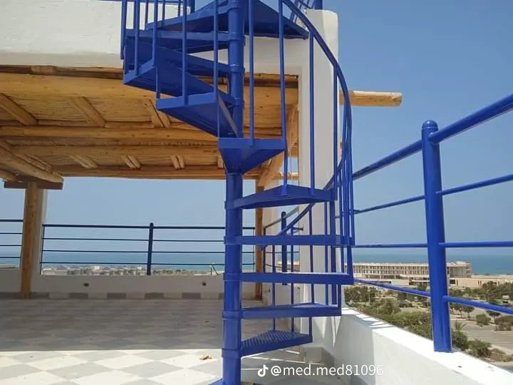 Escalier en colimacon métallique bleu en bord de mer