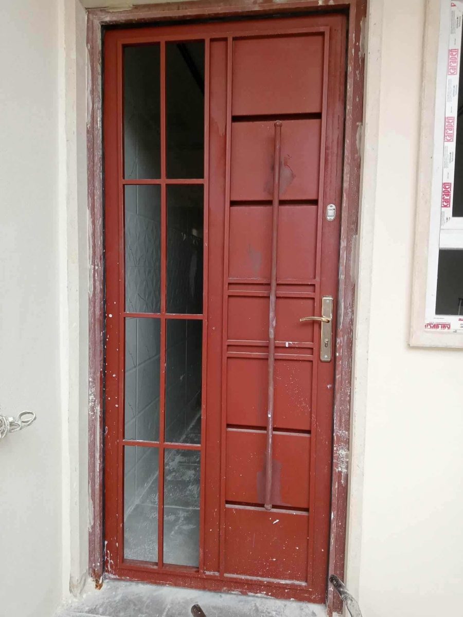 Porte d'entrée en acier rouge à imposte vitrée et barre de tirage