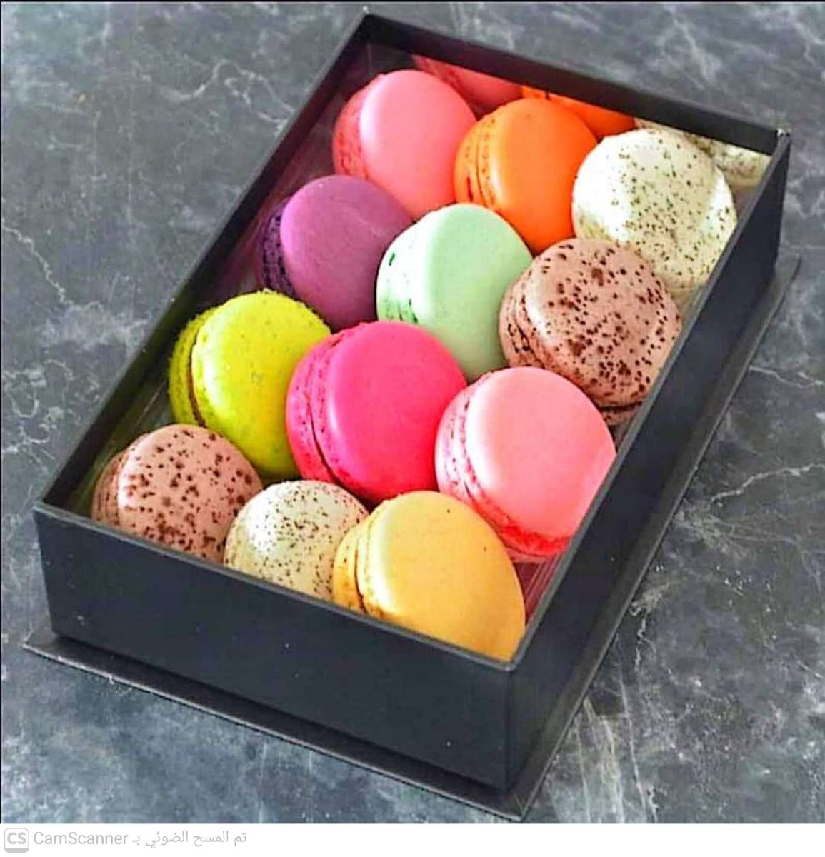 Boîte de macarons multicolores sur un plan de marbre