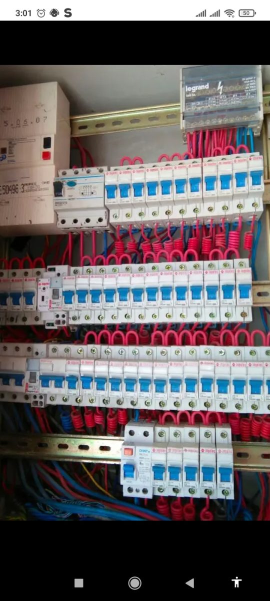 Grand tableau électrique à nombreux disjoncteurs et câblage rouge