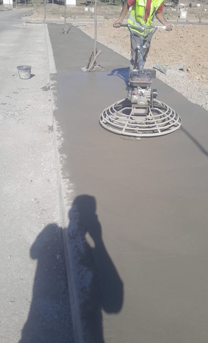 Lissage de béton frais à la truelle mécanique sur un trottoir