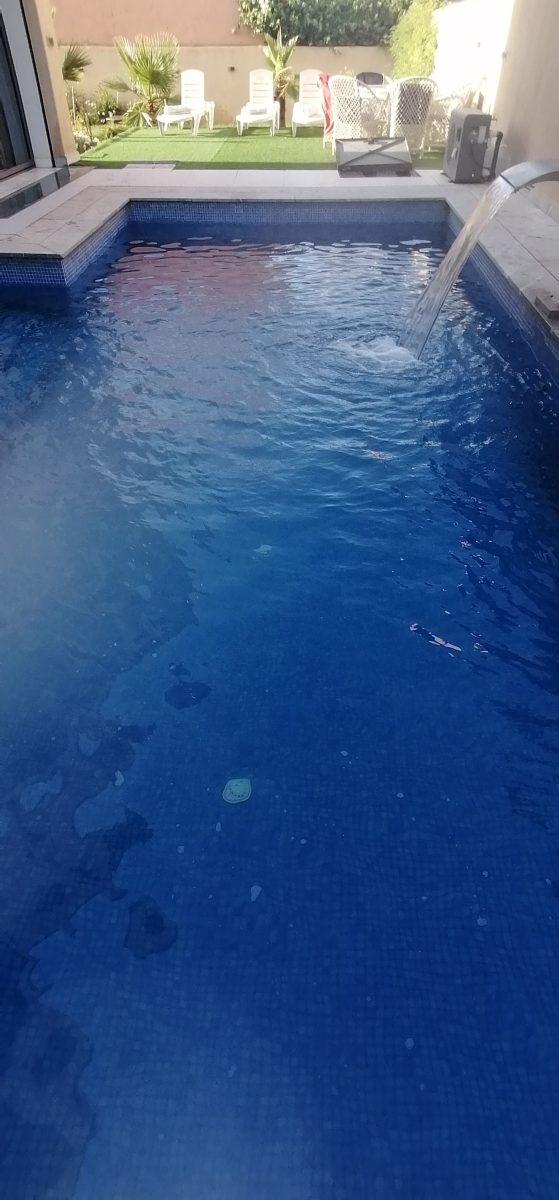 Piscine à lame d'eau en cascade et mosaïque bleu foncé