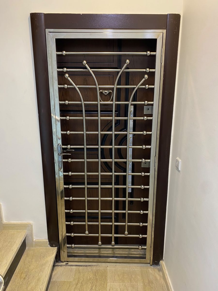 Grille de porte d'entrée en inox poli à barreaux et volutes