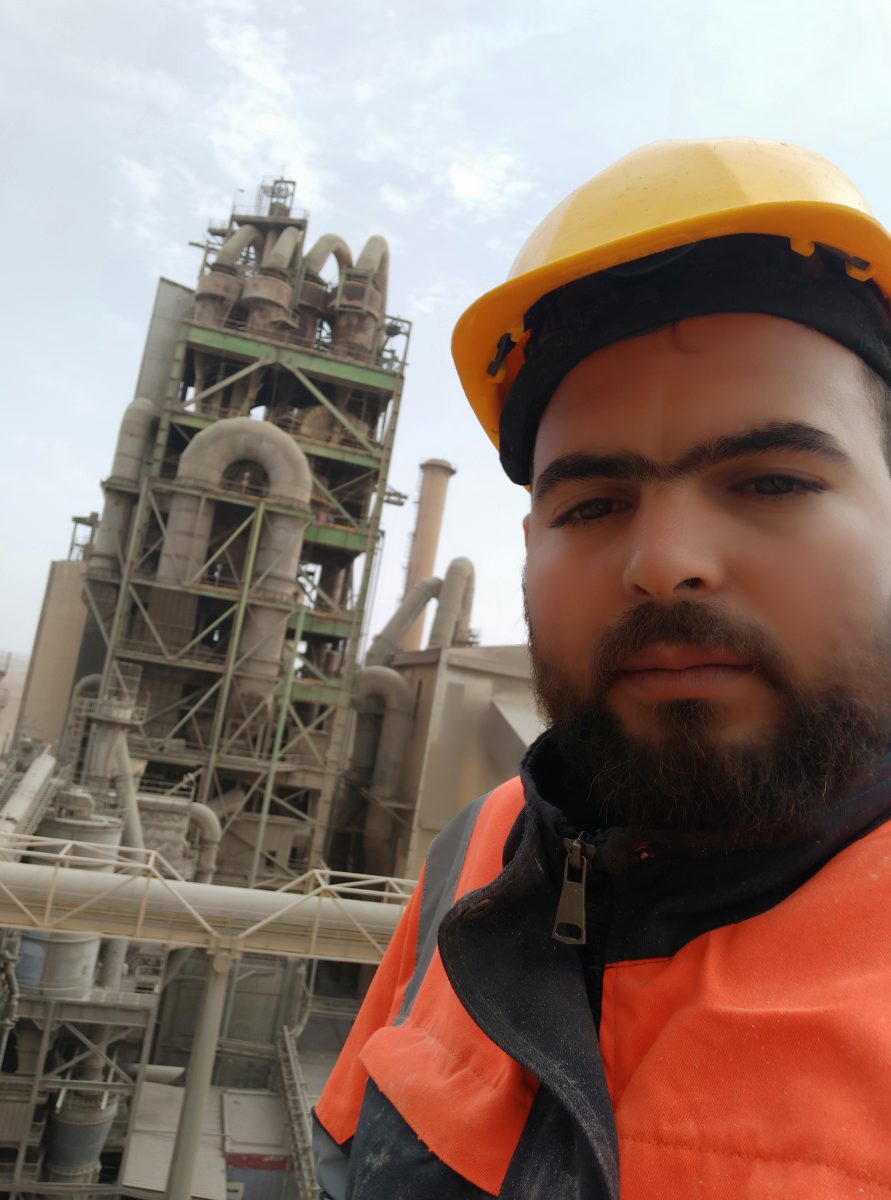 Soudeur en tenue de sécurité devant une usine