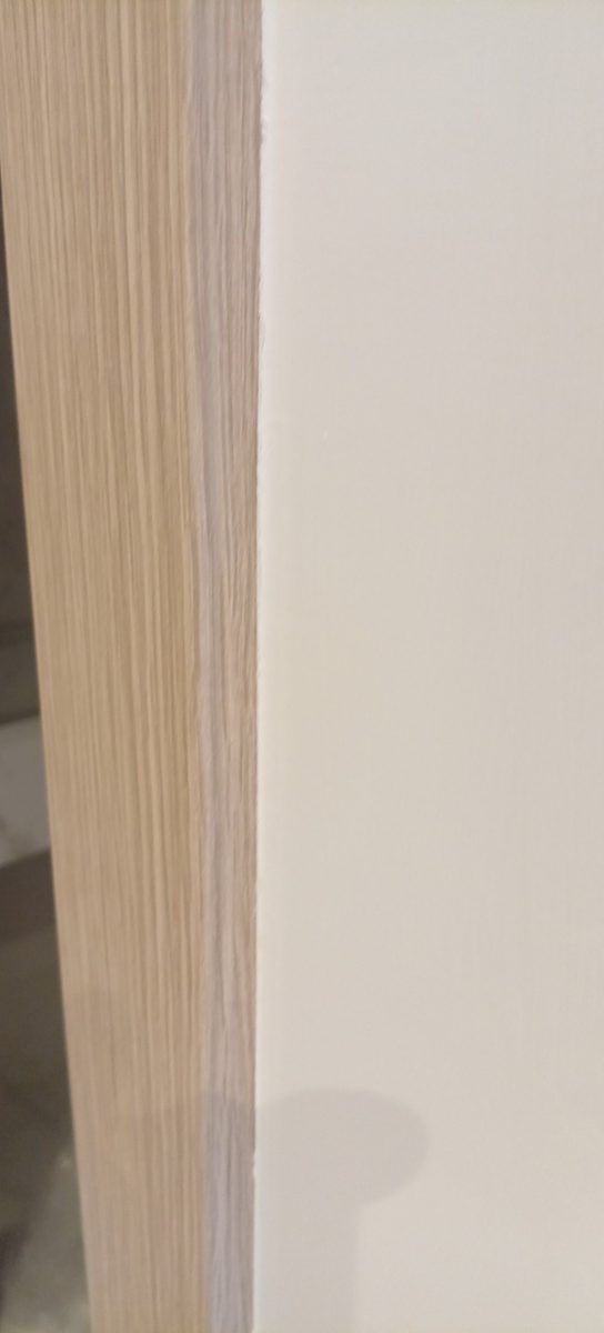 Chambranle de porte en bois clair et mur blanc
