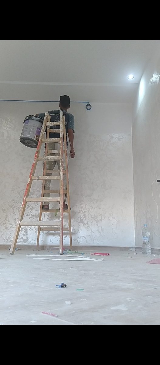 Peintre appliquant un enduit stucco gris sur un mur