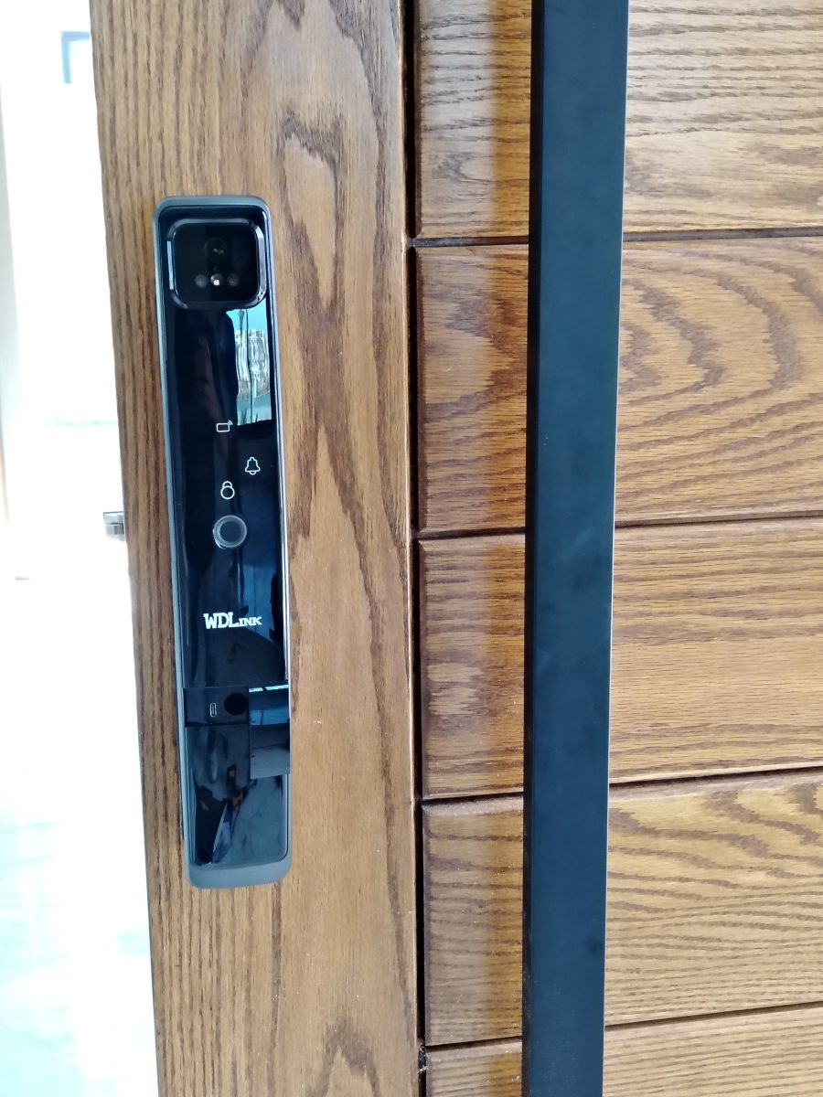 Serrure connectée noire sur porte en bois
