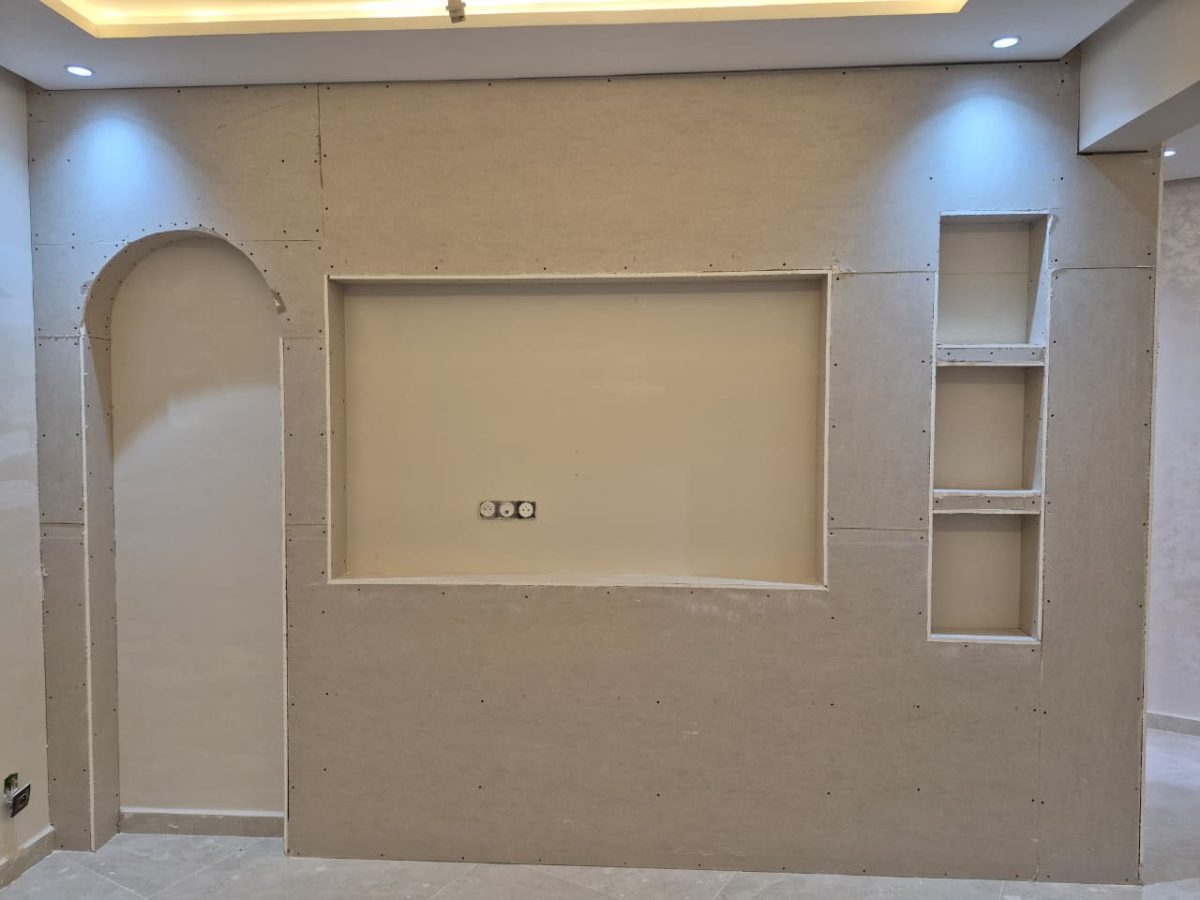 Meuble TV mural en plâtre à niche, arche et étagères, en cours