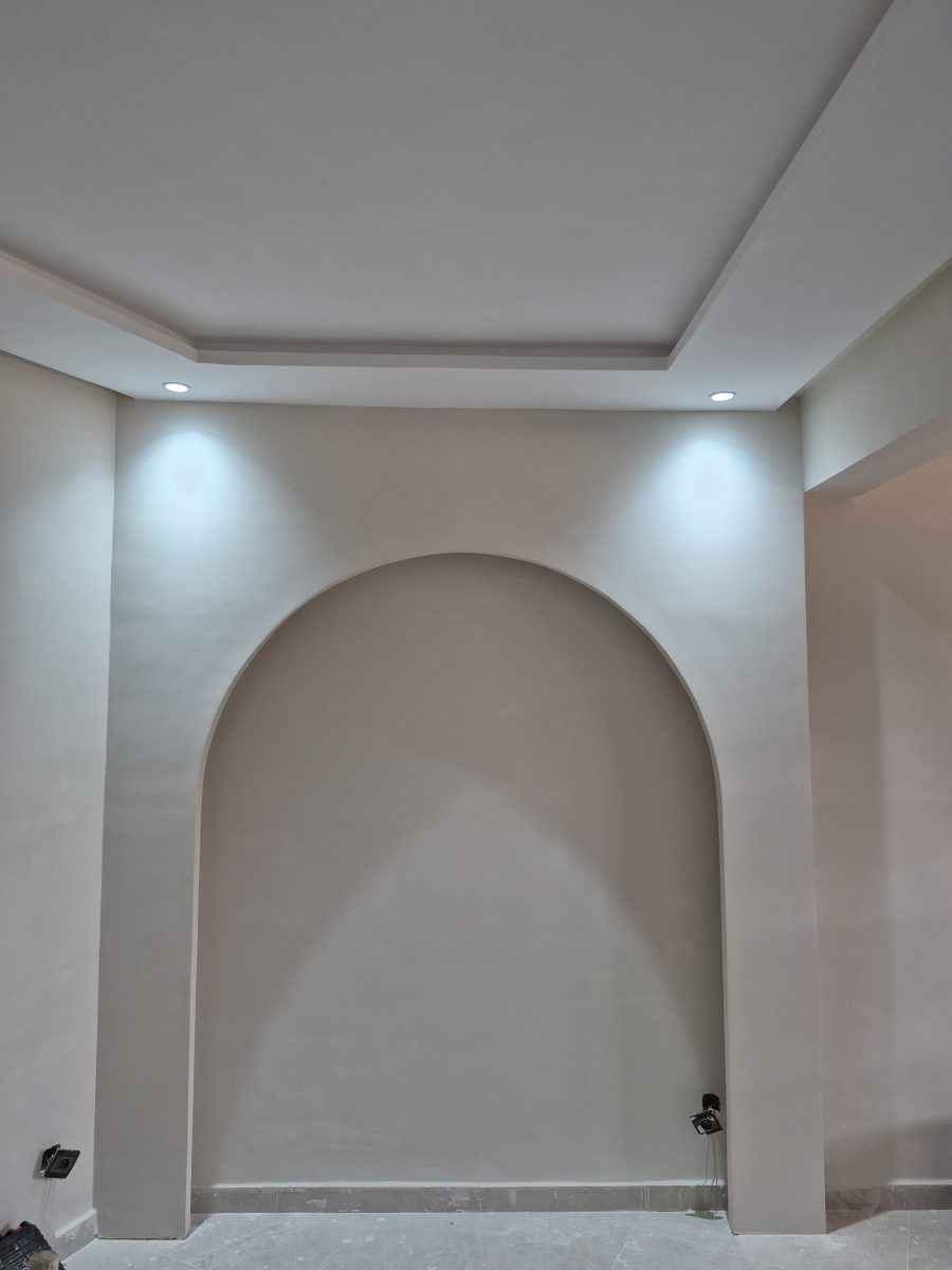 Mur en plâtre à grande arche cintrée et faux plafond à décroché