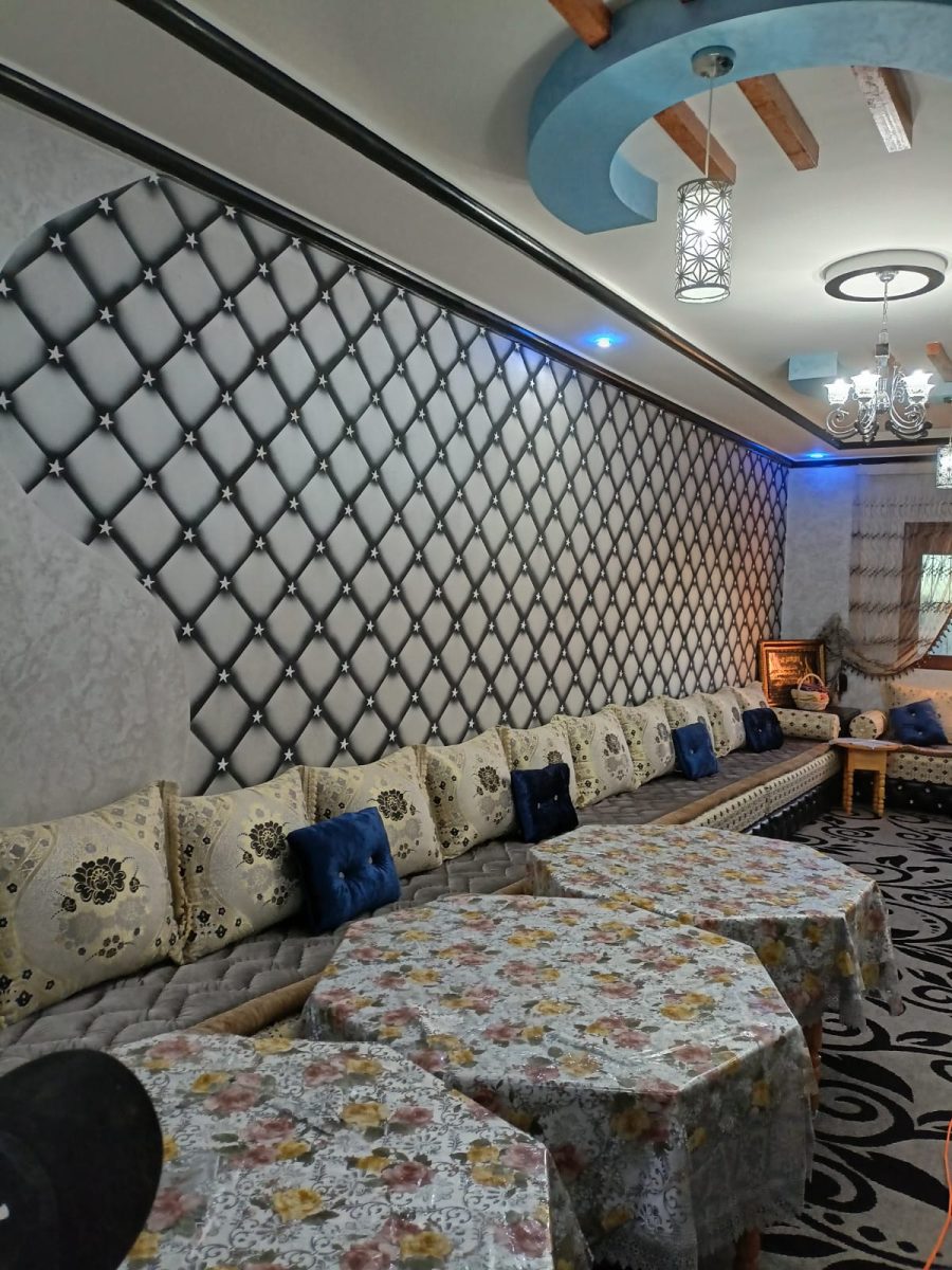 Salon marocain à mur capitonné rétro-éclairé et faux plafond à poutres