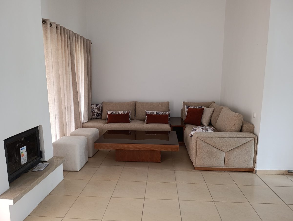 Salon en tissu beige avec canapé, pouf et table basse
