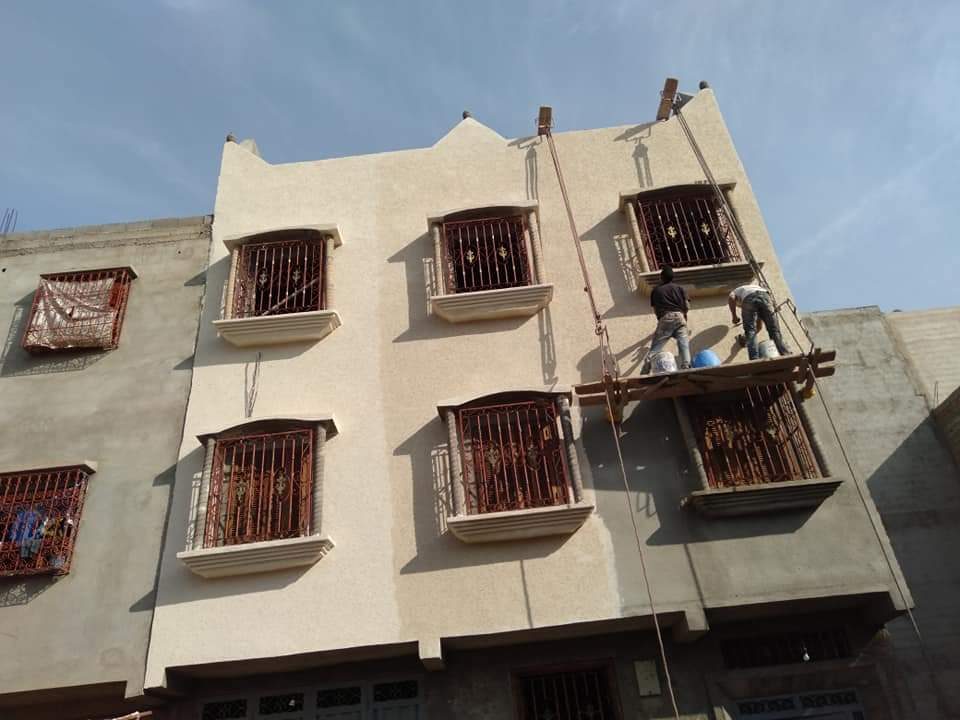 Façade en enduit texturé beige en chantier