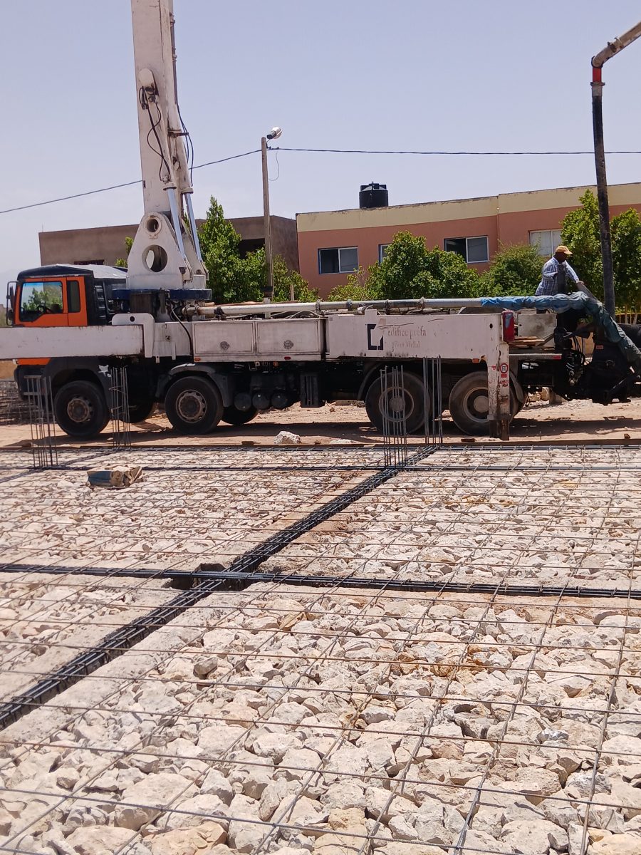 Camion-pompe à béton au-dessus d'un radier ferraillé
