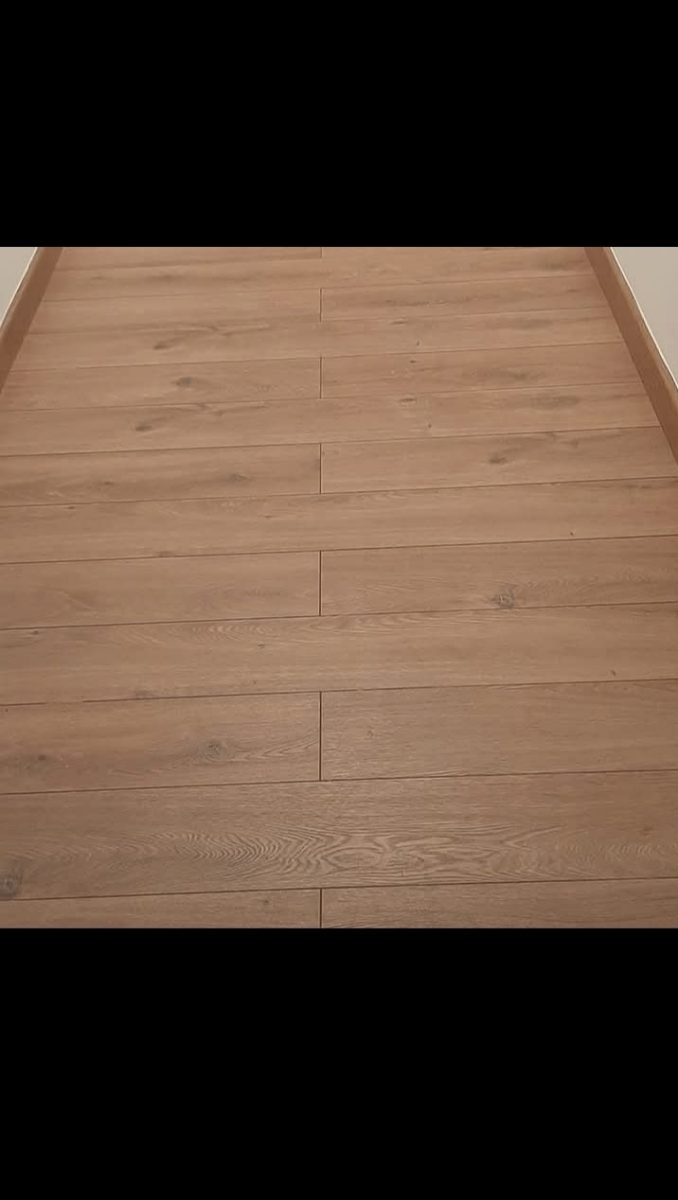 Parquet stratifié bois clair posé le long d'une plinthe