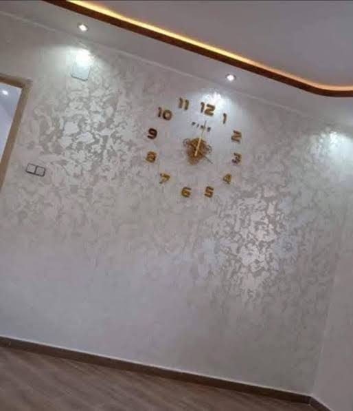 Mur en enduit décoratif nacré crème à horloge dorée