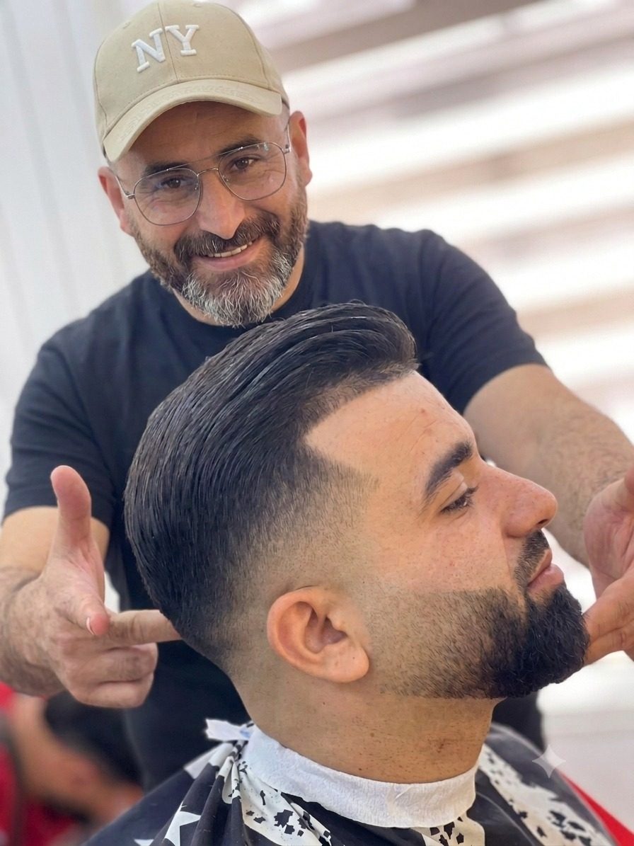 Coiffeur présentant une coupe dégradée et barbe soignée