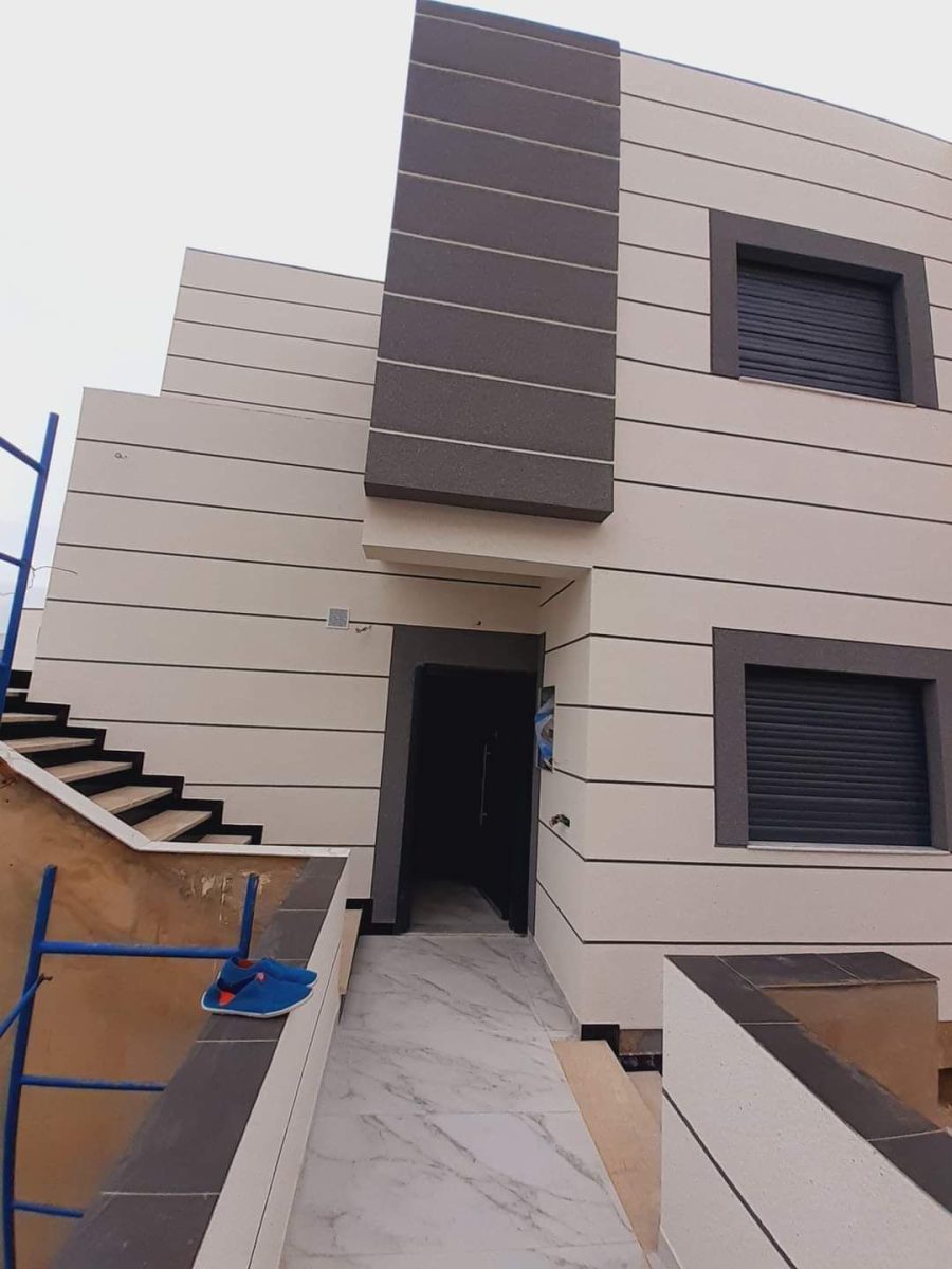 Villa à façade en enduit beige et bandes sombres