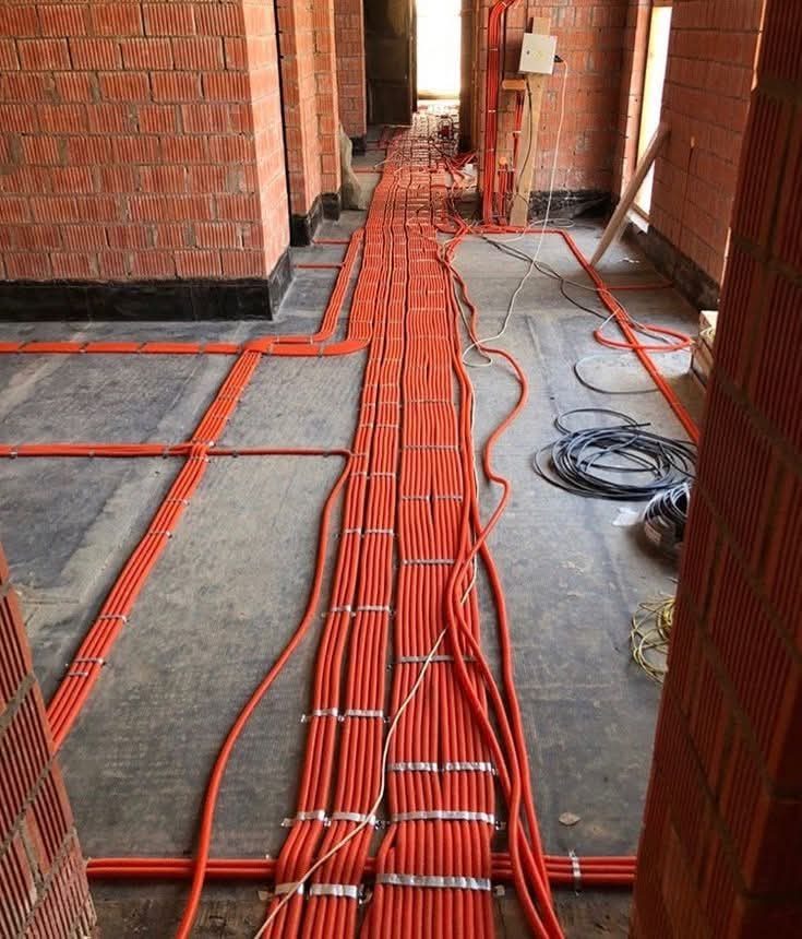 Gaines électriques orange posées au sol d'un chantier