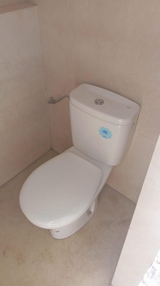 WC monobloc blanc installé en espace carrelé