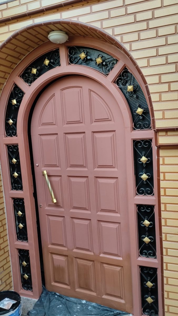 Porte d'entrée cintrée en bois à grilles en fer forgé