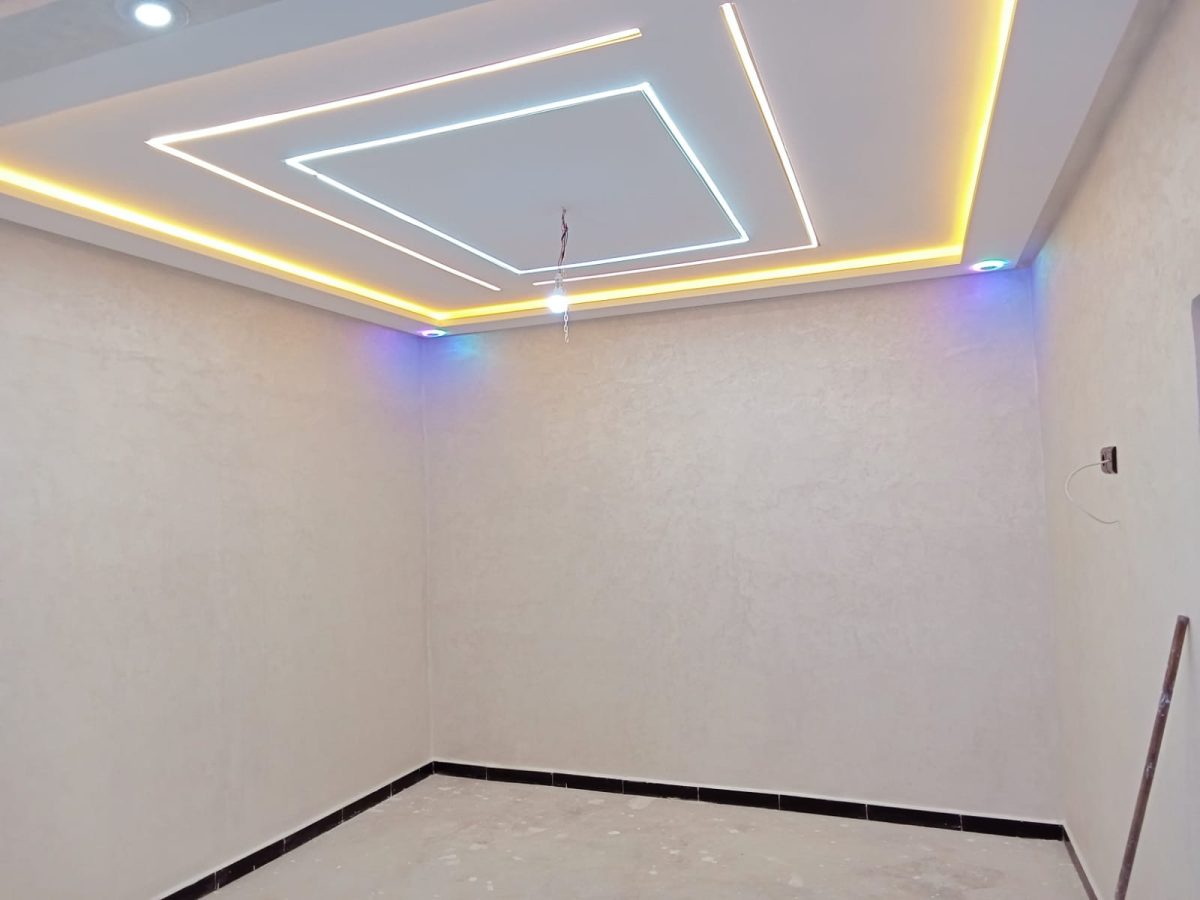 Faux plafond à rubans lumineux et murs en enduit gris