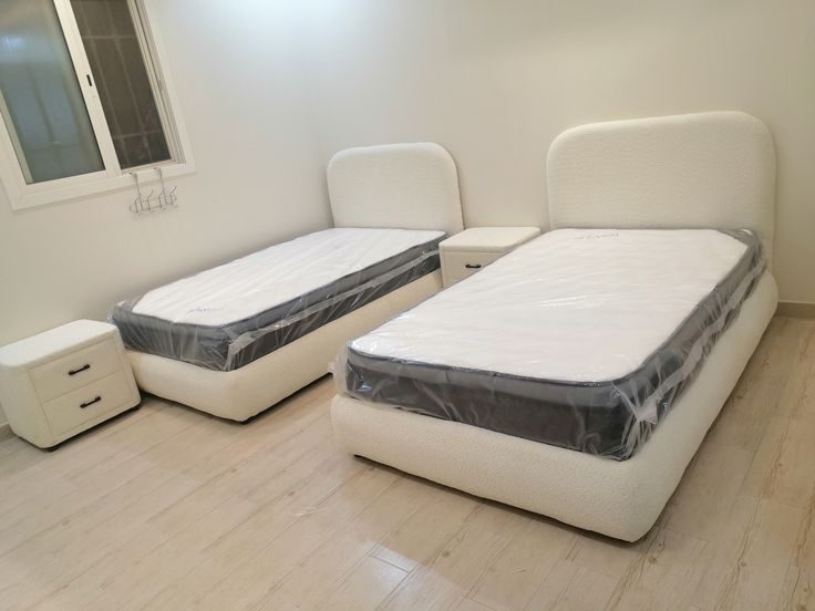 Deux lits simples en tissu bouclé crème à chevets