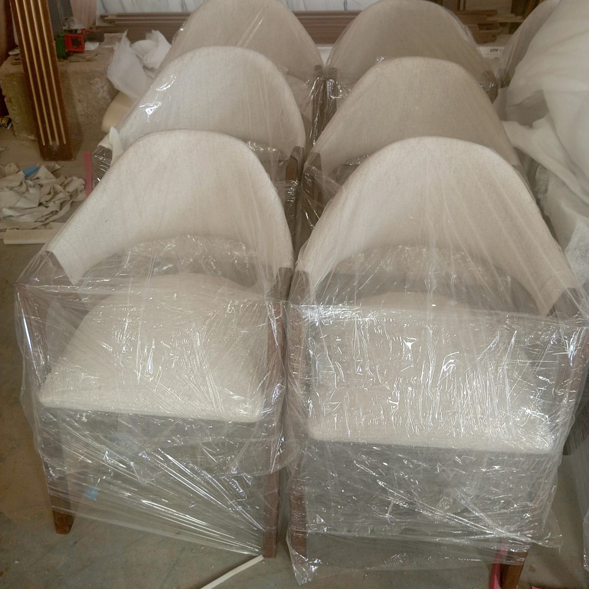 Fauteuils tonneau en tissu écru alignés en atelier