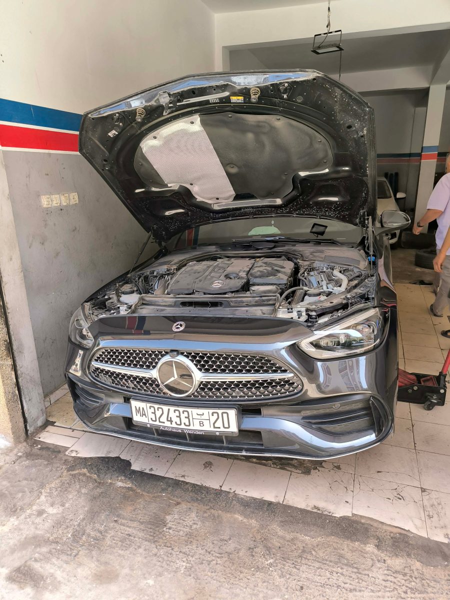 Berline grise au capot ouvert dans un garage