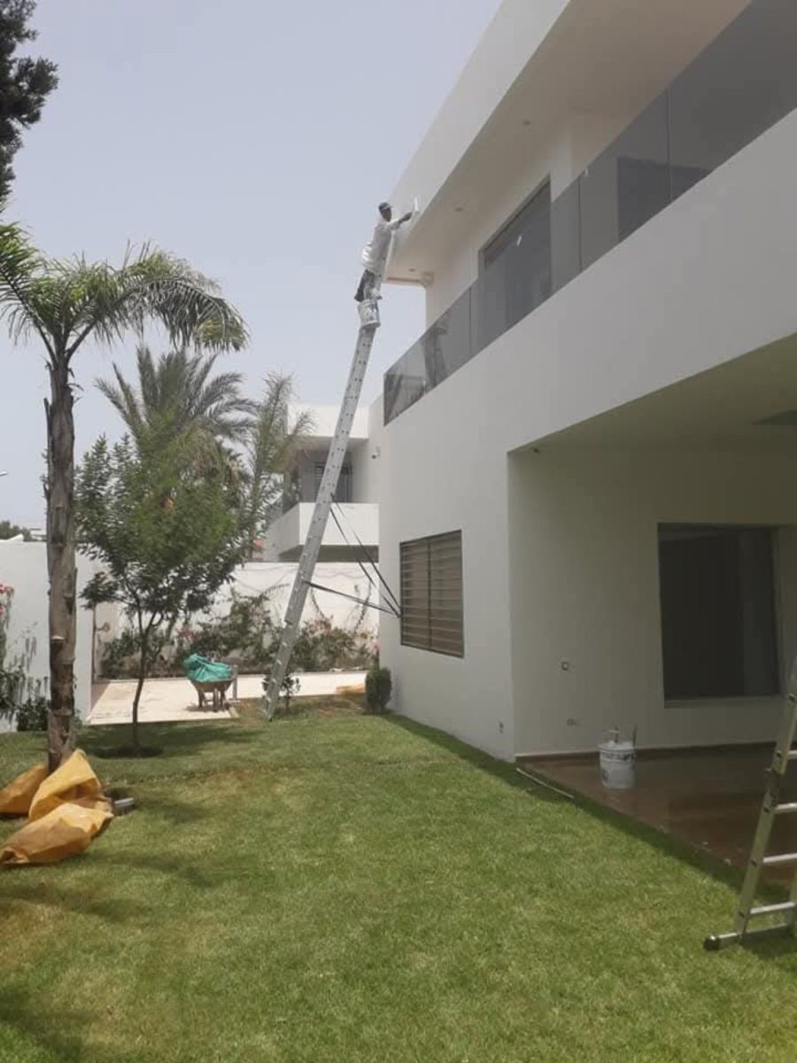 Peinture de l'avant-toit d'une villa sur échelle
