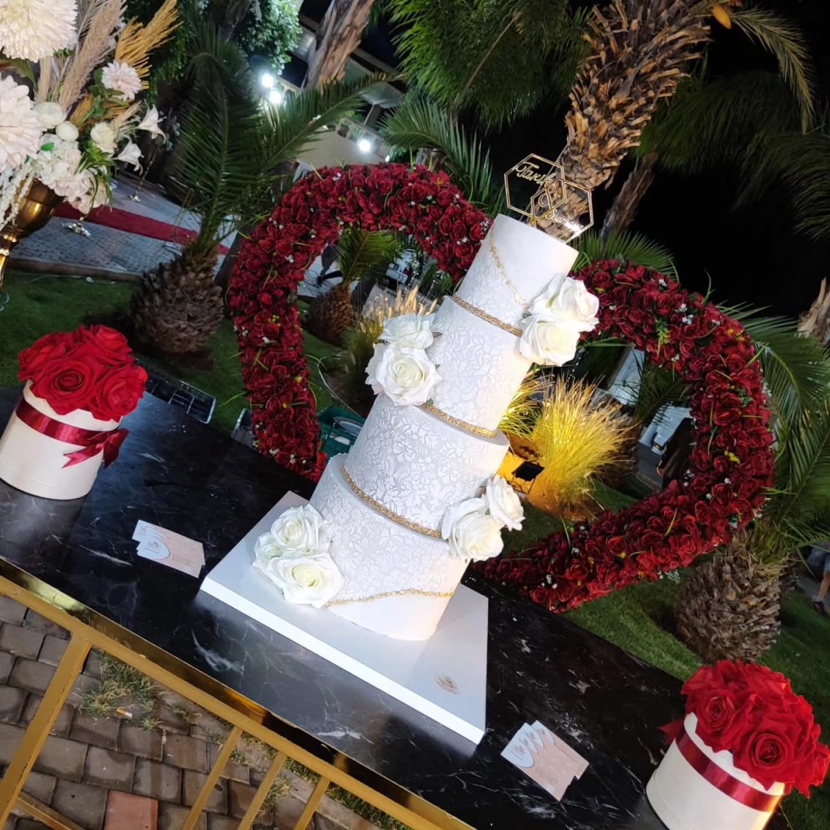 Wedding cake devant une arche de roses rouges