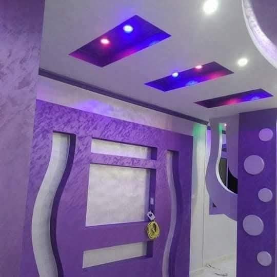 Salon à faux plafond violet et mur télé découpé