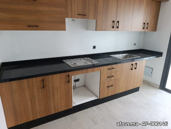 Cuisine équipée en bois avec plan en granit noir et plaque de cuisson