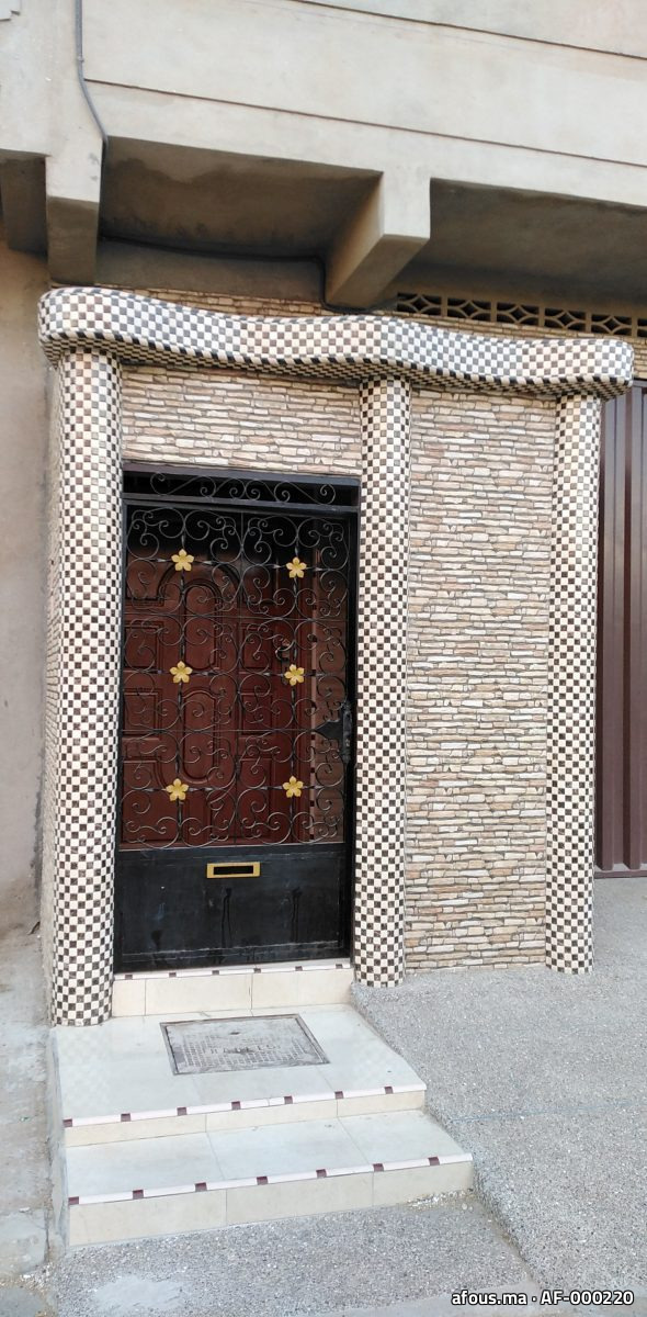 Encadrement d'entrée en carrelage mosaïque damier et pierre, porte en fer forgé — Safi