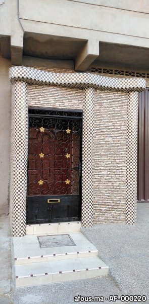 Encadrement d'entrée en carrelage mosaïque damier et pierre, porte en fer forgé