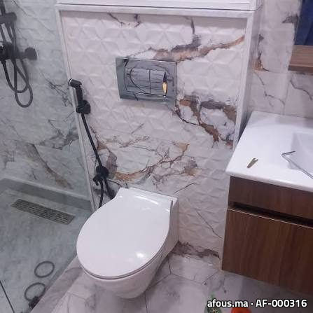 WC suspendu avec plaque de commande dans une salle de bain effet marbre — Meknès
