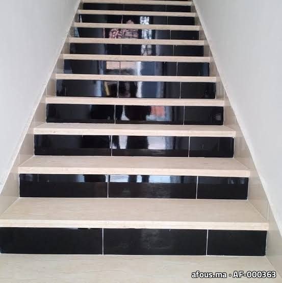 Escalier carrelé à contremarches noires et marches beige