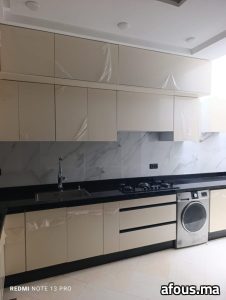 Cuisine laquée crème à plan en granit noir et crédence effet marbre — Meknès