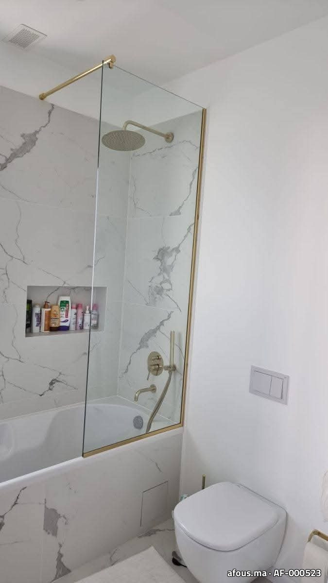 Pare-baignoire en verre à cadre laiton doré dans une salle de bain — Rabat