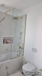 Pare-baignoire en verre à cadre laiton doré dans une salle de bain — Rabat