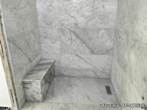 Cabine de hammam habillée de marbre blanc veiné avec banquette