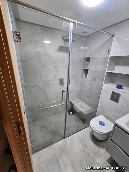 Paroi de douche en verre à cadre chromé dans une salle de bain en marbre gris