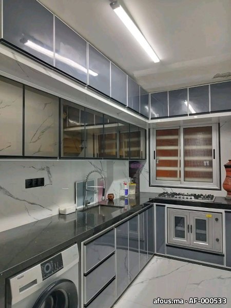 Cuisine en aluminium gris avec vitrines, plan foncé et fenêtre coulissante