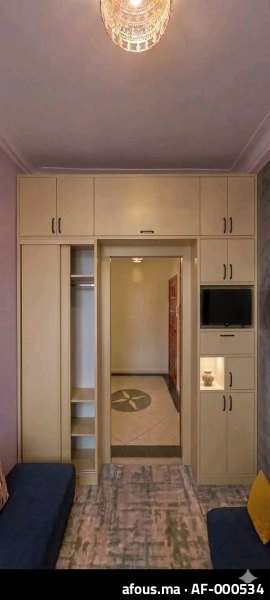 Rangements sur mesure beige encadrant un passage, avec niche TV